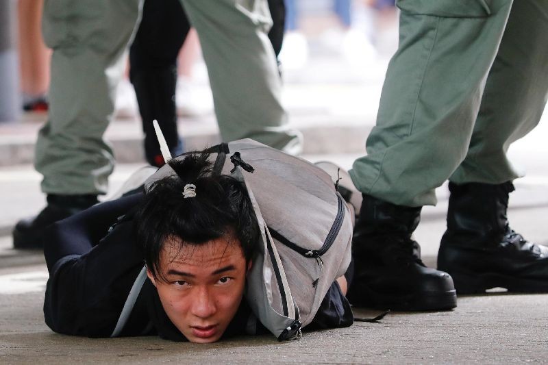 A man lies on the ground as he is detained by riot police during a march against the national security law at the anniversary of Hong Kong's handover to China from Britain in Hong Kong, China. (Photo by Tyrone Siu/Reuters)